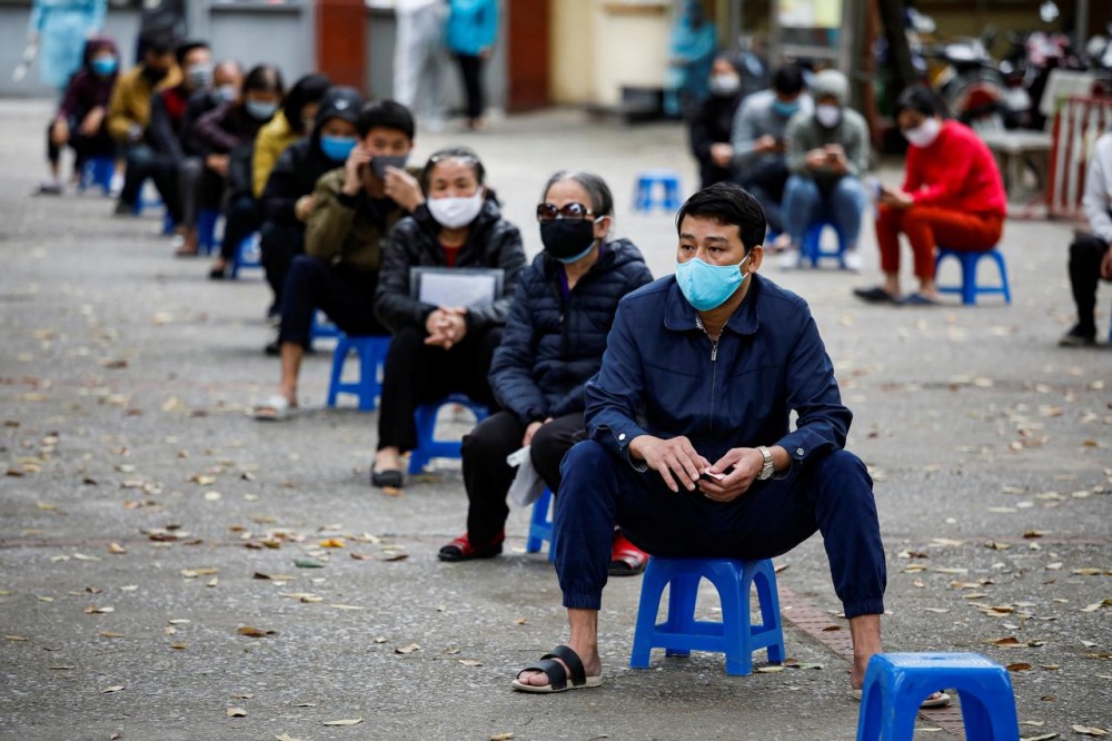 Residents wearing protective masks wait for coronavirus testing at a makeshift rapid testing center in Hanoi, Vietnam March 31, 2020. REUTERS/Kham